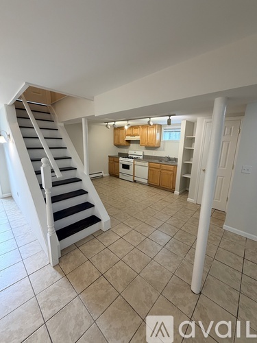 A white staircase with black steps leads to a kitchen area.