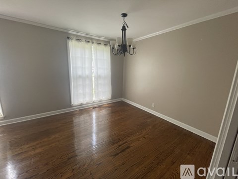 A room with wooden flooring and a chandelier.