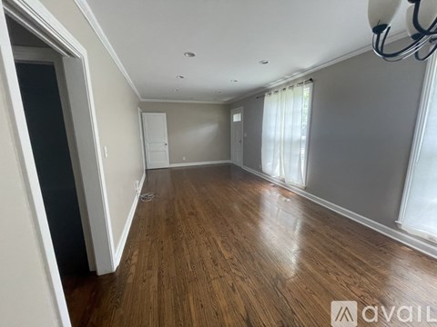A spacious room with wooden flooring and white walls.