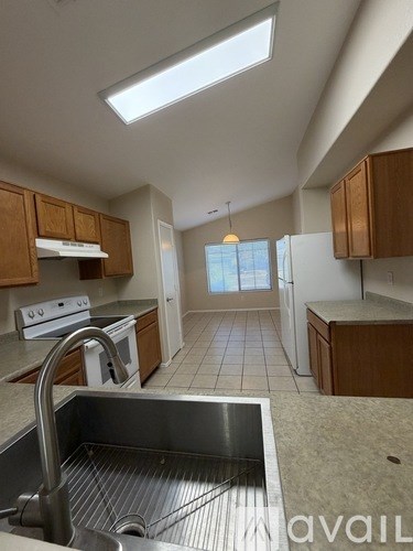 A kitchen with a stainless steel sink and wooden cabinets.