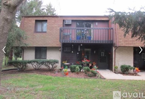 A house with a balcony and a tree in front.