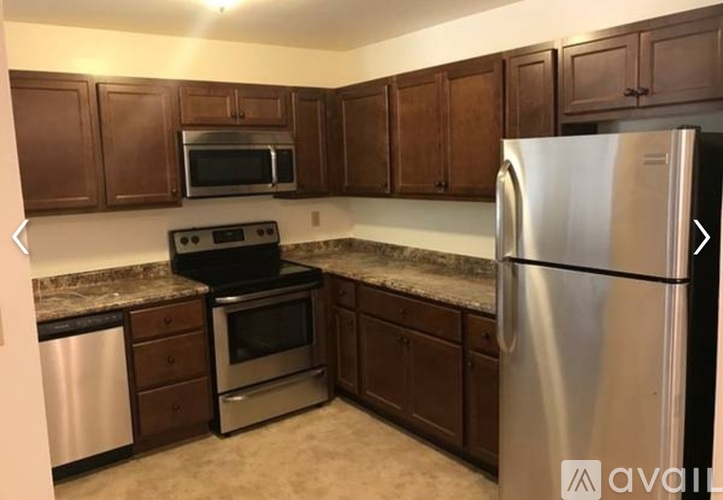 A kitchen with brown cabinets and a stainless steel refrigerator.