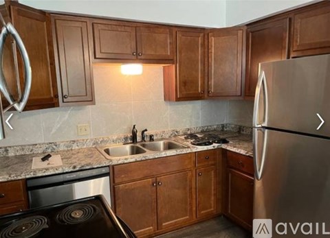 A kitchen with wooden cabinets and a stainless steel refrigerator.