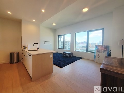 A spacious room with a kitchen island and a view of the city through large windows.