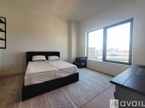 A bedroom with a large bed and a window overlooking a cityscape.
