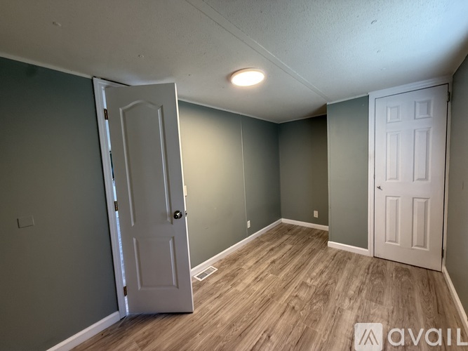 A room with a white door and a wooden floor.