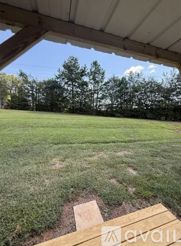 A grassy field with trees in the background and a wooden structure in the foreground.