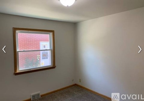 A room with a window and a view of a red building outside.