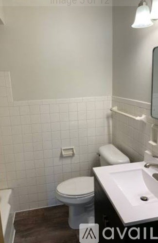 A white toilet sits next to a white sink in a small bathroom.