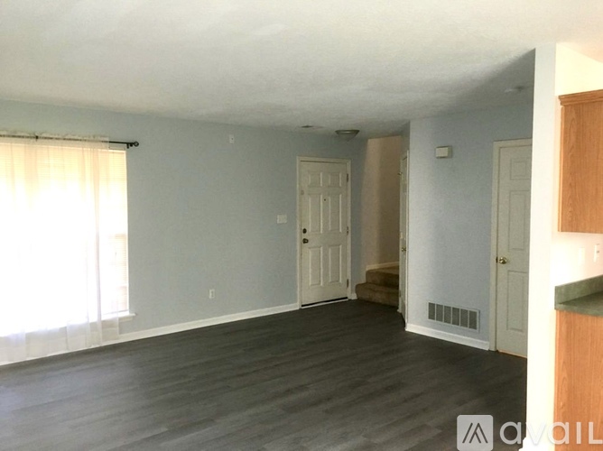 A spacious room with wooden floors and white walls.