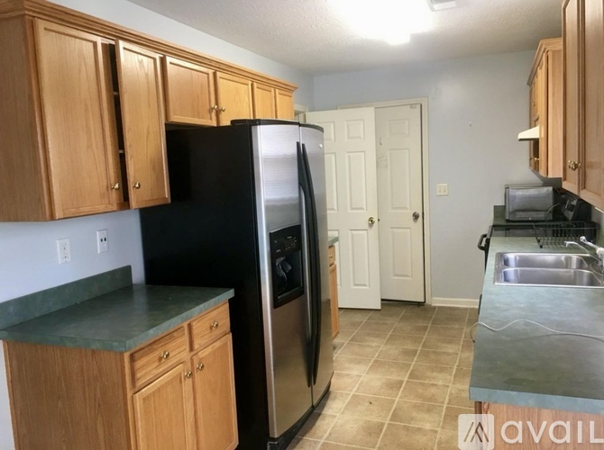 A room with wooden floors and a kitchen area with cabinets and a counter.