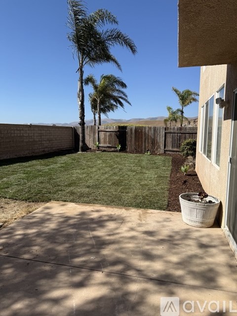 A patio with a concrete floor and a white planter on the edge of a grassy yard.