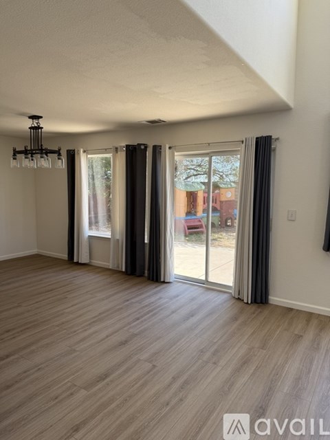 A room with a chandelier, sliding glass doors, and wooden flooring.