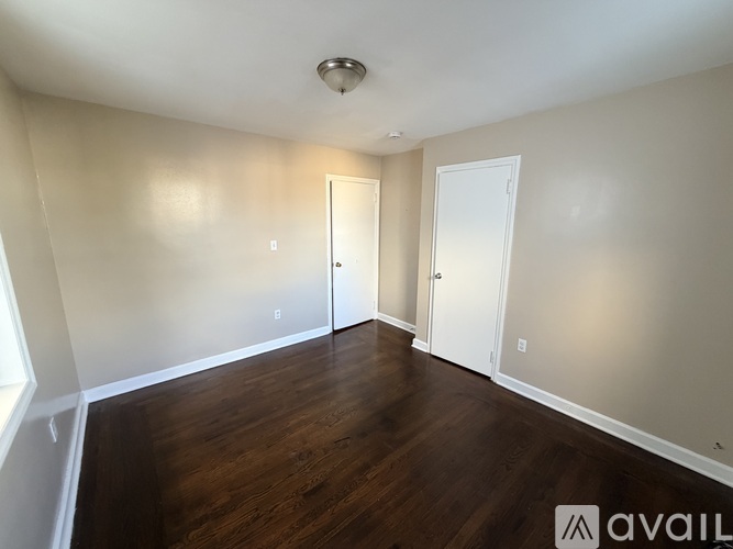 A room with wooden floors and two doors.