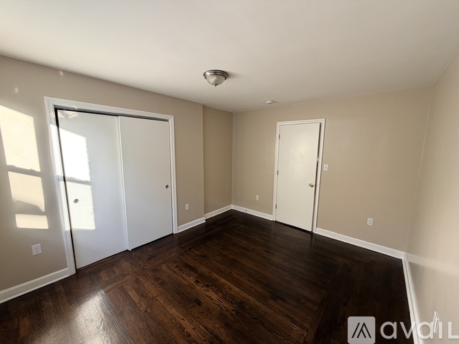 A room with wooden floors and white walls, with a window on the left side.