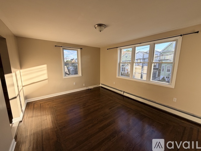 A room with wooden floors and a large window with a view of buildings outside.