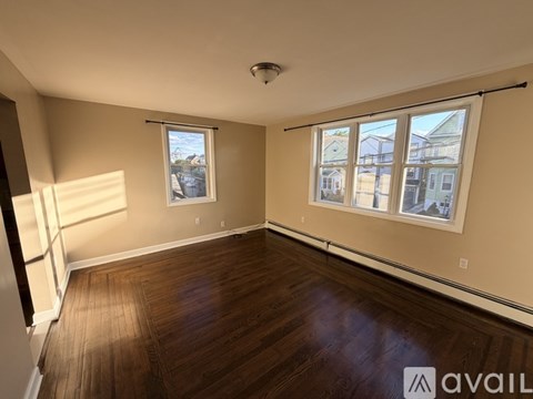 A room with wooden floors and a large window with a view of buildings outside.