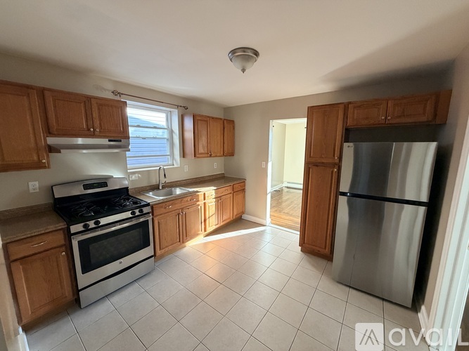 A kitchen with wooden cabinets and a stainless steel refrigerator.