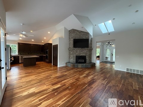 A spacious living room with wooden flooring and a fireplace.