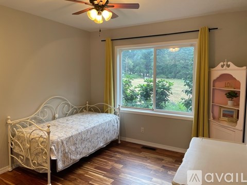 A bedroom with a white bed and a ceiling fan.