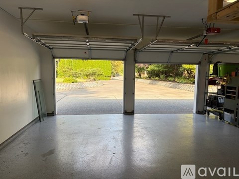A spacious garage with a concrete floor and open doors leading to a driveway.