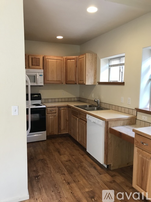 A kitchen with wooden cabinets and a white dishwasher.
