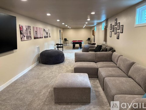 A living room with a grey sofa set and a black bean bag chair.