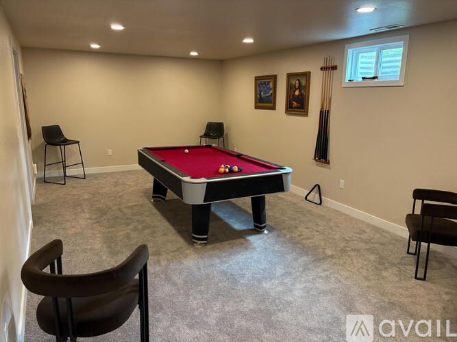 A room with a pool table and chairs.