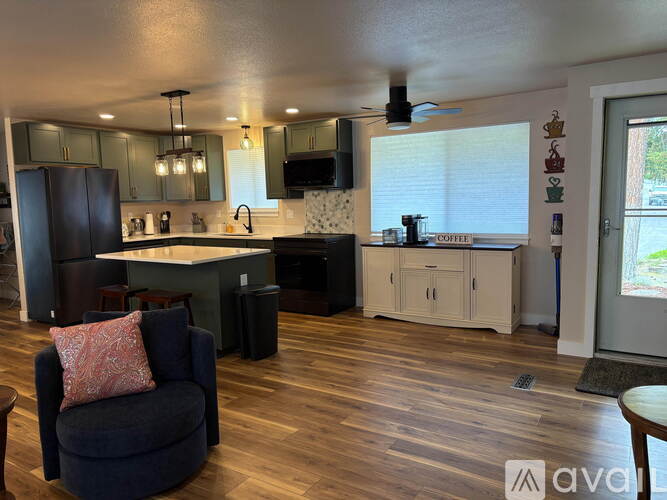 A kitchen with a black refrigerator and a wooden floor.