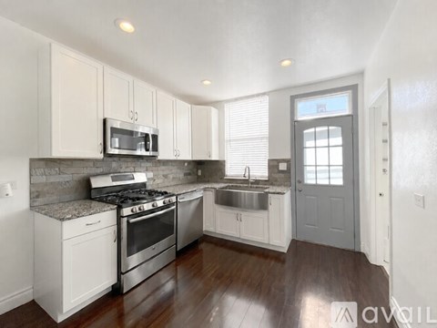 A kitchen with white cabinets and a grey door.