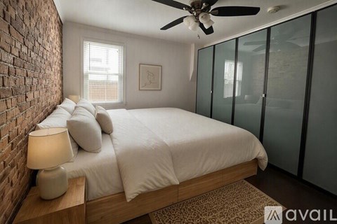 A bedroom with a brick wall and a bed with white bedding.