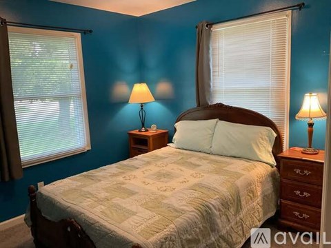 A bedroom with a bed, two lamps, and a window.