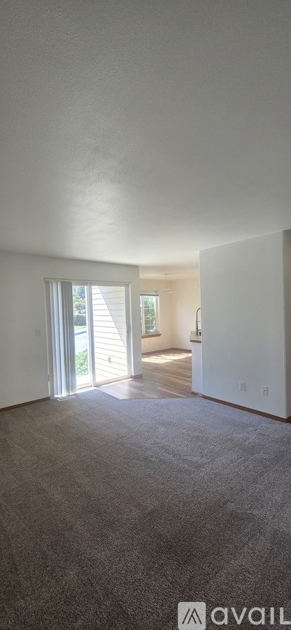 A carpeted room with a doorway leading to another room.