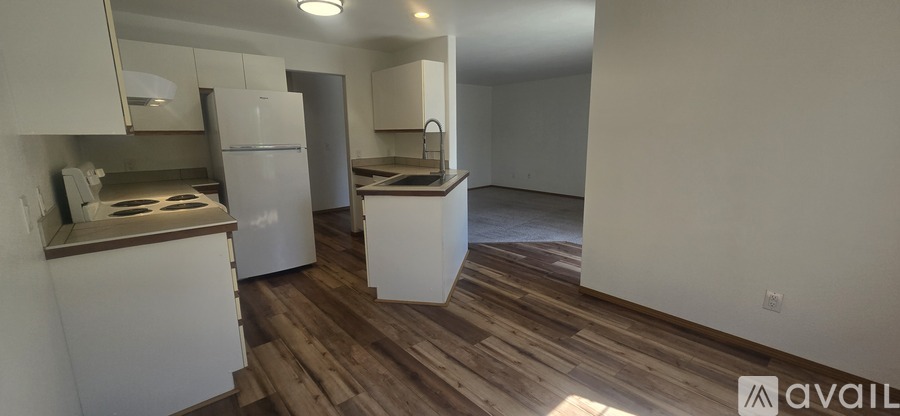 A kitchen with white appliances and wooden floors.