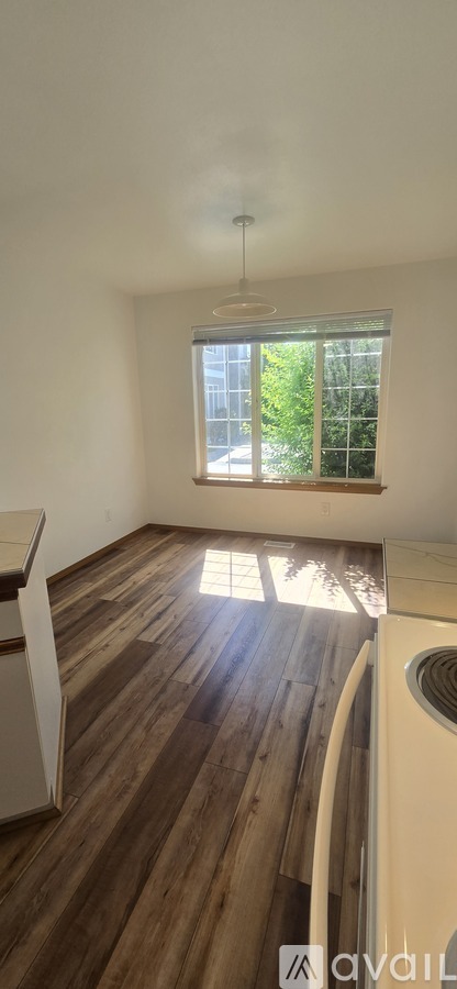 A room with wooden floors and a window letting in sunlight.