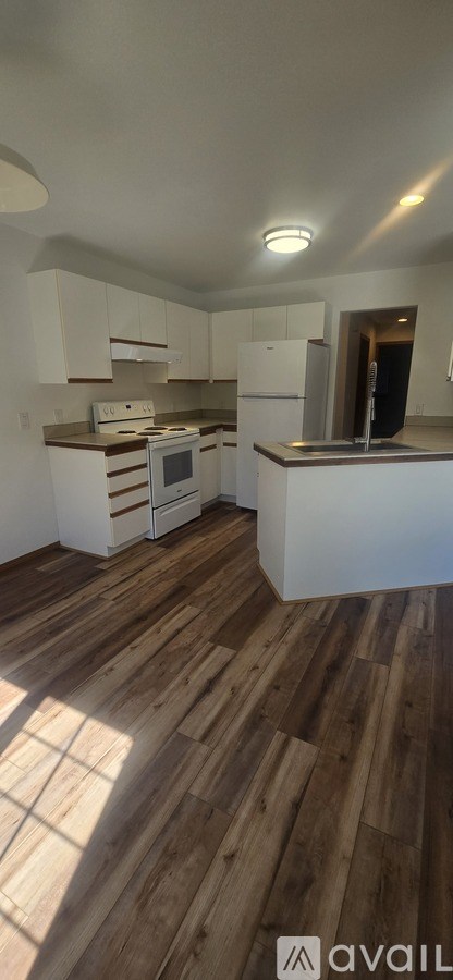A kitchen with white cabinets and a wooden floor.