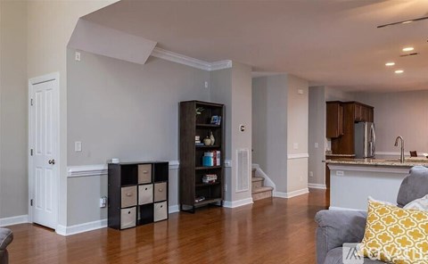 A living room with a grey couch and a black bookshelf.
