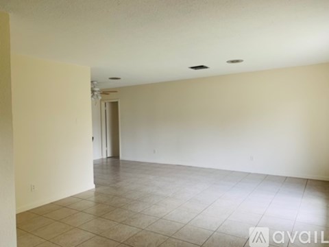 A spacious room with tiled flooring and a doorway leading to another room.