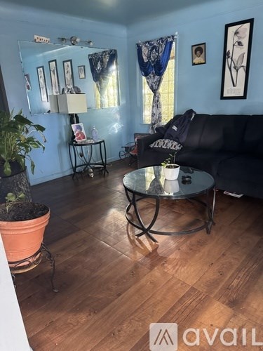 A living room with a black couch and a glass coffee table.