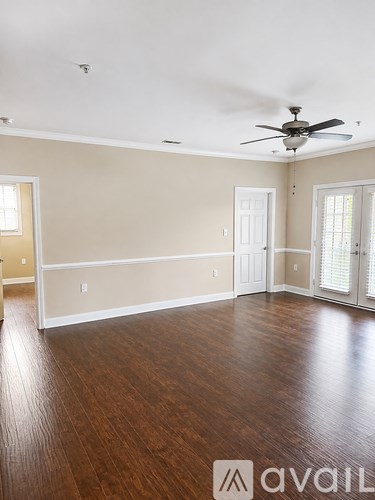 A spacious room with wood flooring and a ceiling fan.