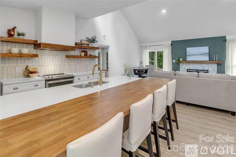 A kitchen with a long wooden table and white chairs is for sale.