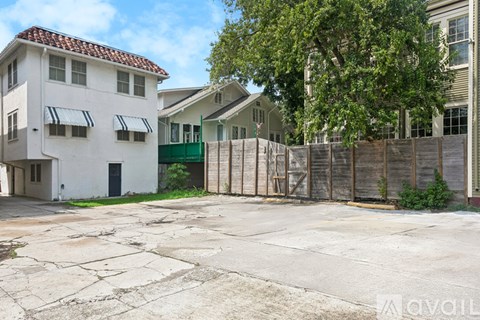 A white building with a red roof is surrounded by a wooden fence.