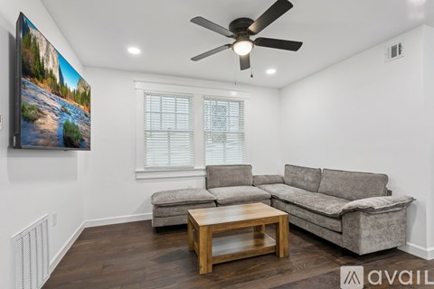 A living room with a grey couch, a wooden coffee table, and a painting on the wall.