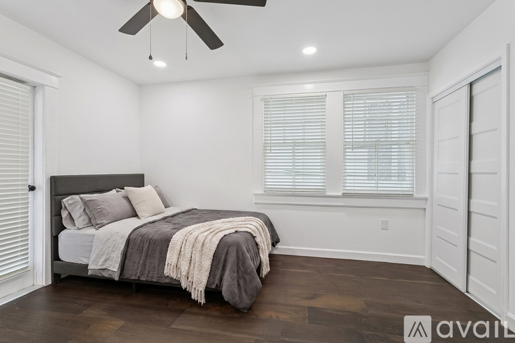 A bedroom with a bed, a ceiling fan, and a window with blinds.