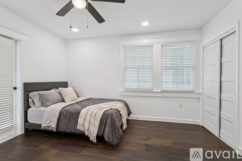 A bedroom with a bed, a ceiling fan, and a window with blinds.