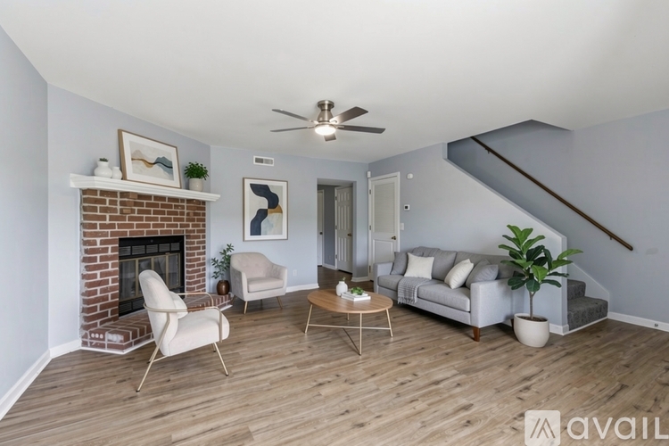 A living room with a fireplace, two chairs, a couch, and a plant.