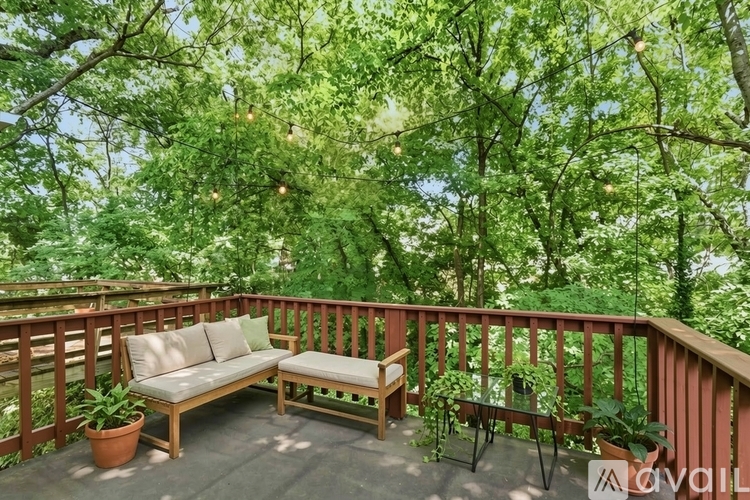 A wooden bench and table are on a deck with a view of trees.