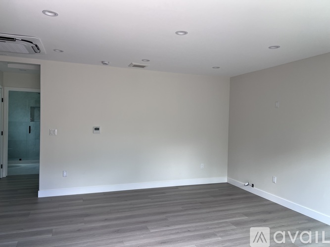 A spacious room with a wooden floor and white walls.