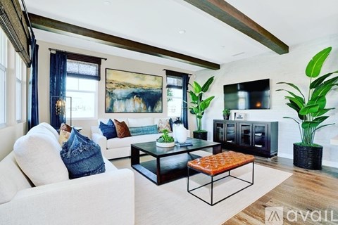A living room with a white couch and a painting on the wall.