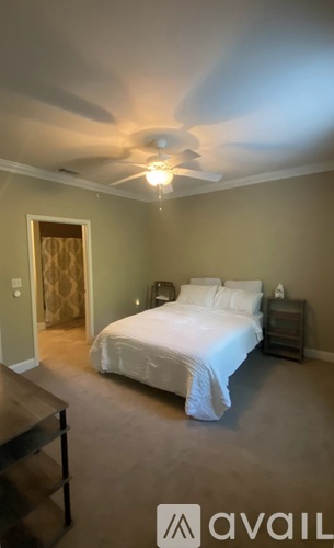 A bedroom with a bed, nightstand, and a ceiling fan.